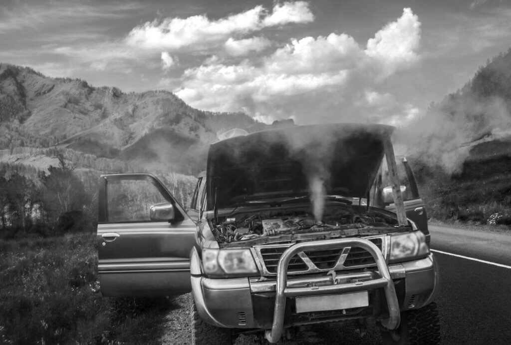 Overheated car on the side of the road in bright sunlight with smoking engine